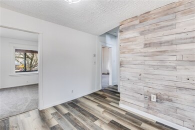 Empty room featuring wooden walls, a textured ceiling, and wood finished floors