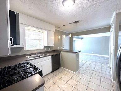 Kitchen featuring white cabinets, ornamental molding, light tile patterned floors, black appliances, and pendant lighting