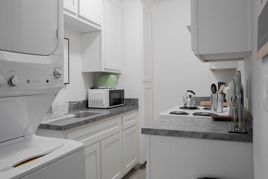 Kitchen and stackable washer and dryer with views of the upper cabinetry in the kitchen.