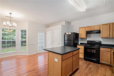 Kitchen featuring black appliances, dark countertops, a textured ceiling, a kitchen island, and dark wood finished floors