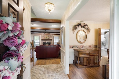 Foyer with a textured ceiling, a stone fireplace, crown molding, wood finished floors, and ceiling fan