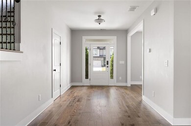 Unfurnished living room with a high ceiling, stairs, dark wood finished floors, a chandelier, and baseboards