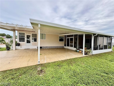 Rear view of house featuring an attached carport, a yard, a sunroom, and a patio area
