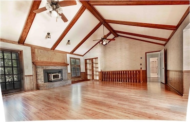 The great room features ceiling fans, light wood-style floors, wainscoting, and high vaulted ceiling