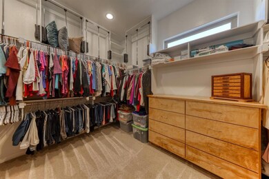 Primary closet with custom system for 3rd row clothing/storage. window to allow for natural lighting.