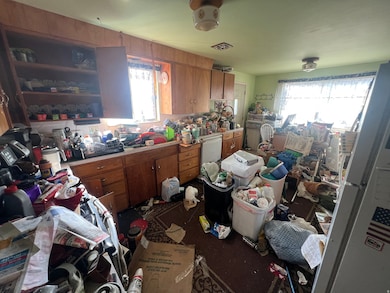 Kitchen with brown cabinetry, plenty of natural light, and freestanding refrigerator
