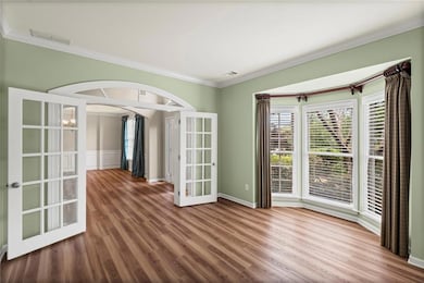 Spare room with french doors, ornamental molding, wood finished floors, and arched walkways