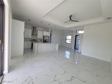 Kitchen featuring a tray ceiling, wall chimney exh