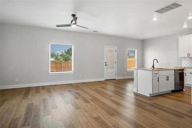 Open-concept living room with large windows and seamless flow into the kitchen and dining.
