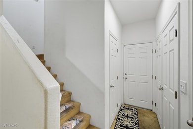 Doorway to outside featuring stairway and carpet flooring