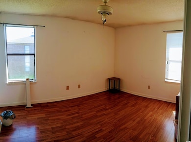 Empty room featuring wood finished floors, a textured ceiling, and baseboards