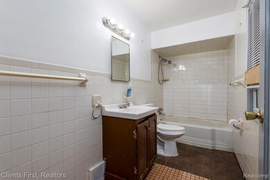 Full bathroom featuring vanity, shower / washtub combination, tile walls, wainscoting, and dark tile patterned flooring