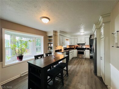 Kitchen with stainless steel appliances, sink, decorative backsplash, dark hardwood / wood-style floors, and white cabinetry