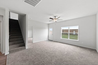 Unfurnished living room featuring stairs, ceiling fan, and carpet floors