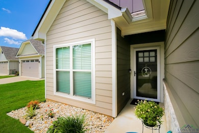 Property entrance featuring a lawn, an attached garage, and driveway