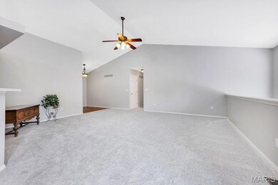 Unfurnished living room with a ceiling fan, vaulted ceiling, and carpet