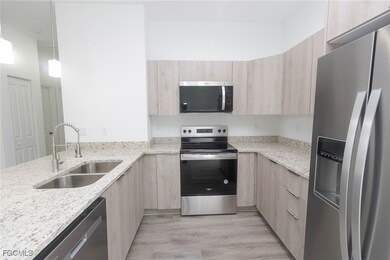 Kitchen featuring light brown cabinets, stainless steel appliances, a sink, light stone countertops, and modern cabinets