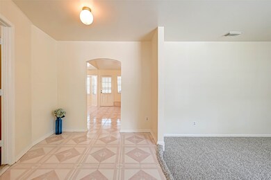 The foyer of this elegant home serves as an inviting introduction to its interior, seamlessly connecting the formal living and dining areas with a graceful archway.