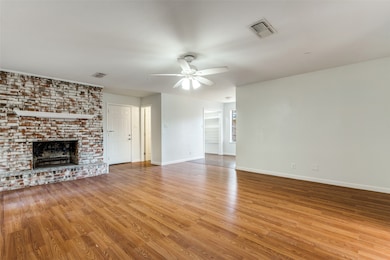 Unfurnished living room featuring a brick fireplace, light wood-style floors, and a ceiling fan