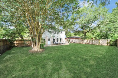 Spacious backyard with lush green grass, mature tr