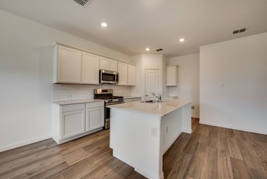 Kitchen with appliances with stainless steel finishes, backsplash, light countertops, light wood finished floors, and recessed lighting
