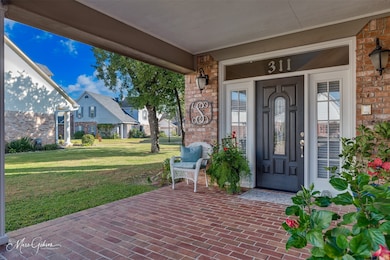 Doorway to property featuring a porch, a yard, and brick siding