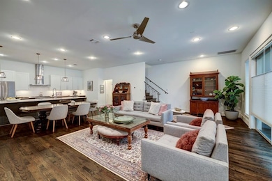 This open-concept living room showcases rich wood flooring, recessed lighting and large windows that create an airy, inviting atmosphere
