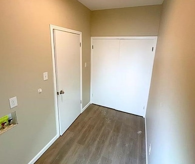 Corridor with dark wood-style flooring and baseboards