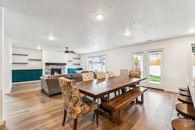 Dining area with light wood-style floors, a fireplace, a textured ceiling, recessed lighting, and a ceiling fan