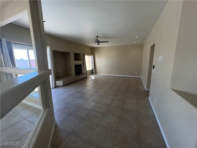 Unfurnished living room with a fireplace, a ceiling fan, and light tile patterned floors