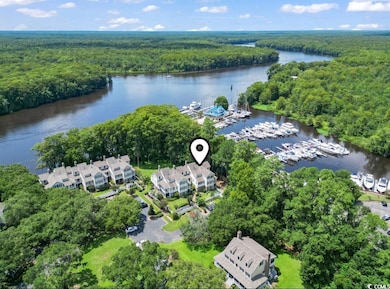 Aerial view of property and surrounding area featuring a marina and a nearby body of water