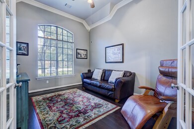 Office/study with wood flooring, crown molding, 8ft French doors, currently being used as a TV room.