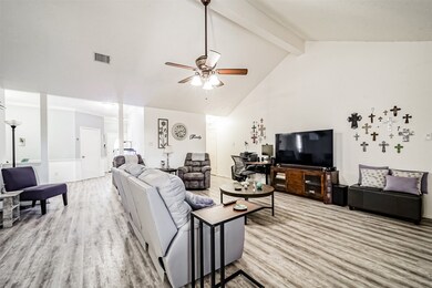 This inviting Family Room features soaring high ceilings adorned with beautiful wood beam accents. A ceiling fan with an elegant light fixture completes the space, adding both style and functionality.