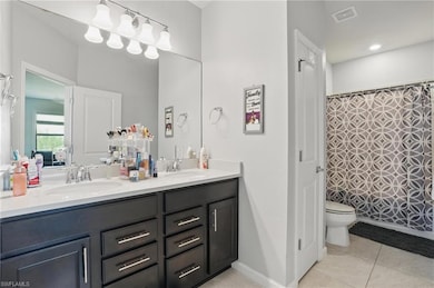 Bathroom featuring double vanity, toilet, tile patterned floors, and curtained shower