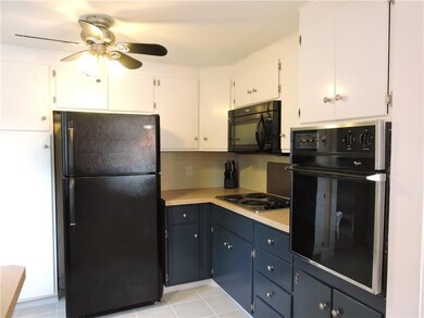 Kitchen has lots of cabinets, tile...