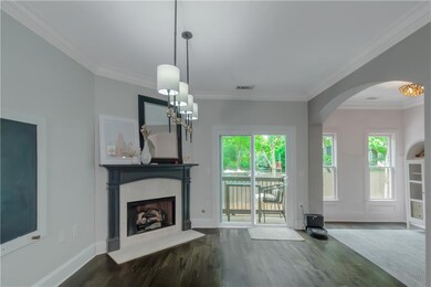 Unfurnished living room featuring crown molding, arched walkways, wood finished floors, a fireplace, and a chandelier