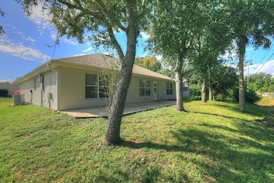 Rear view of property featuring a patio, a yard, and stucco siding