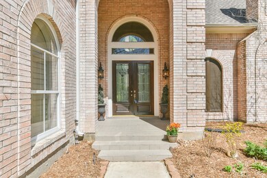 A towering covered porch with an imposing arched entrance makes a grand statement as you take three steps up to the double front doors with leaded glass detailing. Tile flooring and a pair of carriage-style lanterns add character to the entrance.