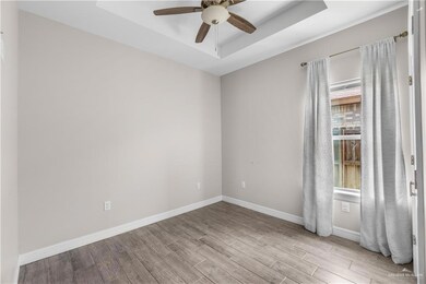 Unfurnished room with wood finished floors, a tray ceiling, and baseboards