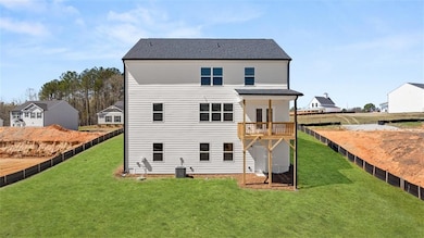 Back of house featuring a lawn, a shingled roof, central AC unit, and a fenced backyard