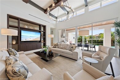 Living room with light tile patterned floors, a notable chandelier, and a towering ceiling
