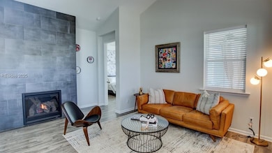 Living room featuring a tiled fireplace, light har