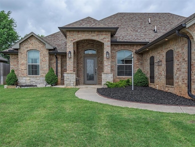 French country inspired facade with a shingled roof, a front yard, and brick siding