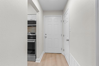 Doorway featuring a textured wall and wood finished floors