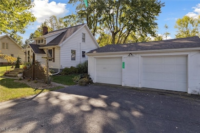 View of side of property featuring a chimney, a garage, a shingled roof, driveway, and a yard