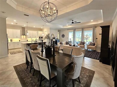 Dining space with a tray ceiling, a chandelier, light tile patterned floors, ornamental molding, and recessed lighting