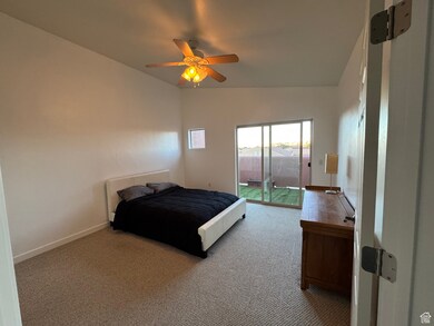 Carpeted bedroom featuring ceiling fan, lofted ceiling, and access to outside