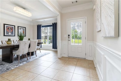 Foyer featuring ornamental molding, healthy amount of natural light, a wainscoted wall, a decorative wall, and light tile patterned floors