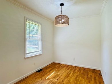 Spare room featuring crown molding, baseboards, and light wood-type flooring