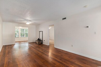 Unfurnished living room with a ceiling fan, dark wood-style flooring, a textured ceiling, and baseboards